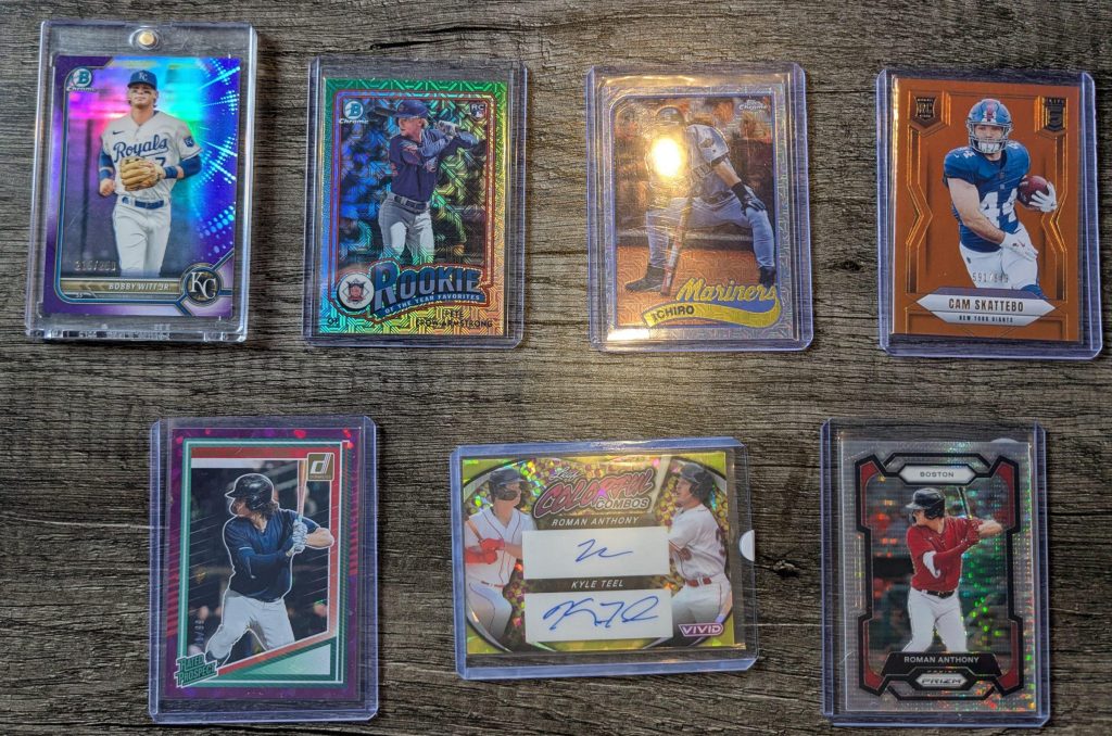 Seven baseball and football trading cards displayed on a wooden table, including a Bobby Witt Jr. purple refractor, Pete Crow‑Armstrong insert, Ichiro mojo refractor, Cam Skattebo orange parallel, two Roman Anthony parallels, and a Roman Anthony/Kyle Teel dual autograph